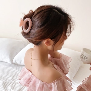 Pink acetate hair claw clip with striped pattern worn by a model in a cozy bedroom