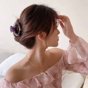 Elegant purple marble acetate hair claw clip and gold heart necklace on woman in floral top