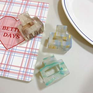 Close-up of three gradient acetate rectangular hair claws on a pink checkered notebook