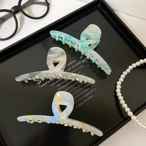 Detail of premium acetate hair claws with iridescent shell texture and handmade marking