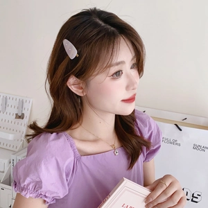 Elegant white acetate hair claw clip with rhinestones and gold necklace on female model