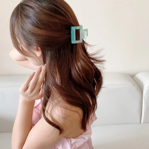 Rectangular acetate hair claw clip with light blue marble pattern on female model