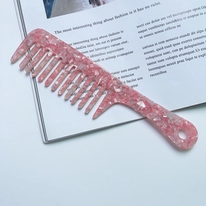 Detailed close-up of pink marble pattern acetate comb with wide teeth and long handle