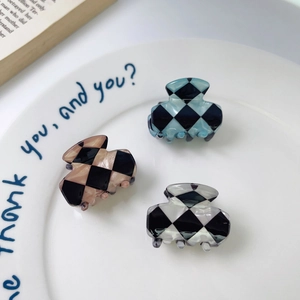 Mini checkered rectangle hair claw clips in blue, brown and black in a ceramic dish
