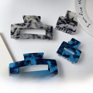 Detailed macro view of square acetate hair claws with blue ink and marble textures