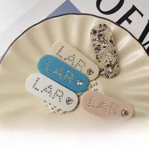 Close-up of acetate hair clips with sparkling rhinestone LAR letters and heart details