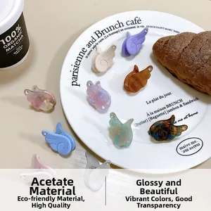 Détails de pinces à cheveux ailes d'ange en acétate marbré avec strass sur une assiette blanche