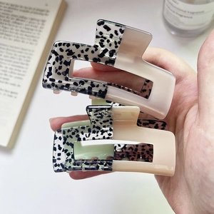 Macro detail of rectangle acetate hair claws in mint green and beige with floral patterns