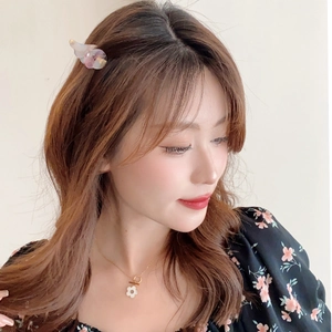 Détail d'une petite pince à cheveux aile d'ange en acétate et collier floral sur un modèle