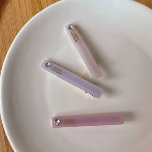 Trois barrettes en acétate aux couleurs pastel avec strass cœur et logo doré élégant