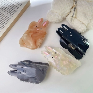 Gros plan de quatre jolies pinces à cheveux lapin en ambre, noir, blanc perle et gris fumé