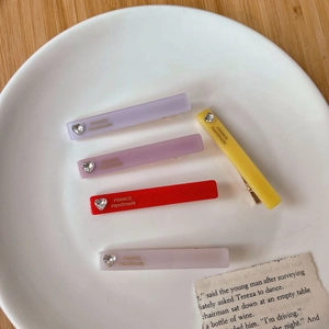 Détail de barrettes rectangulaires en acétate avec strass en forme de cœur colorés