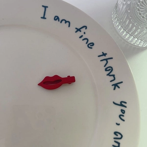 Détail d'une pince à cheveux rouge en forme de lèvres sur une assiette décorative