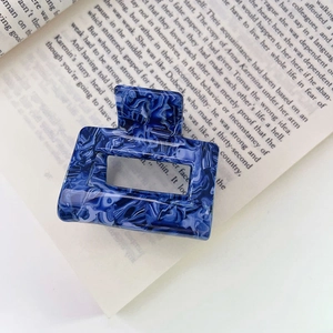 Detail of blue marble cellulose acetate hair claw clip on an open vintage book