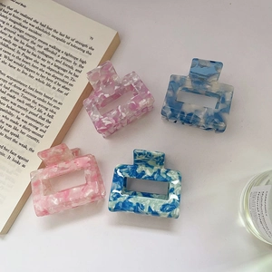 Four elegant acetic acid square hair claws with marble textures in a lifestyle setting