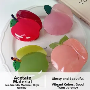 Détail de pinces à cheveux en acétate en forme de pomme et pêche avec fini perlé