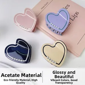 Dettagli di quattro mollette a cuore in acetato con piccole perle in vari colori pastello