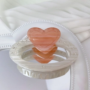 Detailed view of acetic acid heart claw clip with rhinestones reflected on a mirror