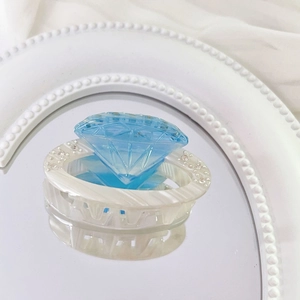 Close-up of marble acetate hair claw clip with large blue rhinestone on a mirror