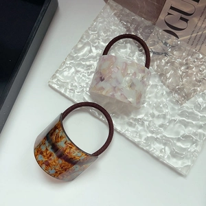 Detail of pink marble and tortoiseshell pattern scrunchies on a glass surface