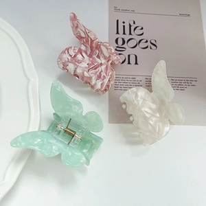 Three acetate butterfly hair claws with marble and pastel finishes on a white background