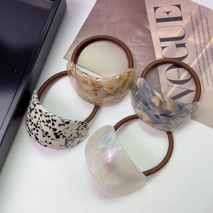 Set of four tortoiseshell and marble texture acetate ponytail holders on a Vogue magazine
