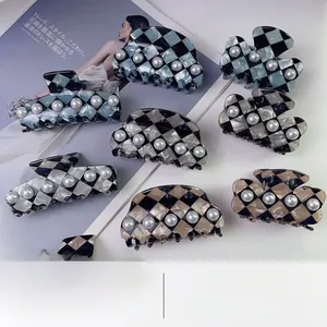 Close-up of checkerboard acetate hair claws with elegant pearl accents and glossy finish