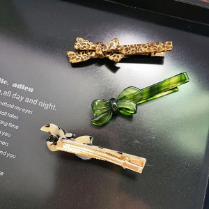 Chic leopard print and translucent green acetate bow hair clips on minimalist display