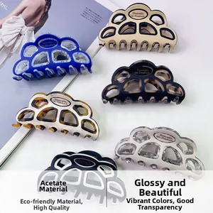 Détail de pinces à cheveux en acétate évidé avec logos métalliques de marque premium