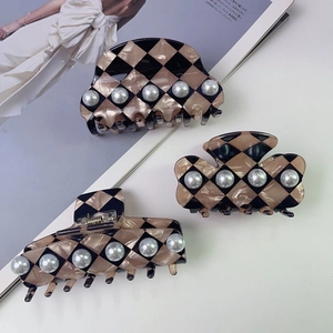 Close-up of three checkered hair claws with elegant faux pearls in a luxury vintage style