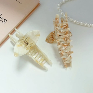 Set of two large acetate hair claws in marble white and amber brown on a white surface