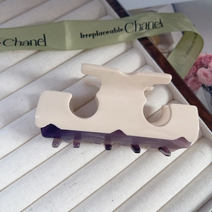 Close-up of dual-tone acetate hair claw clip with cream resin and purple teeth