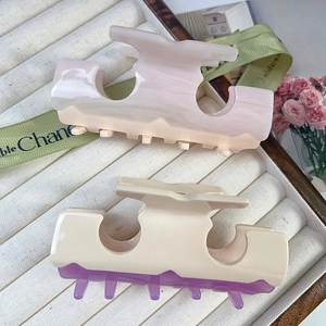Elegant two-tone acetate hair claws in pastel marble colors on beige velvet tray