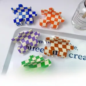 Détail de 5 pinces à cheveux en acétate en forme de puzzle aux motifs à carreaux