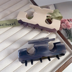 Elegant acetate claw clips in marble blue and cream colors with stylish cut-out design