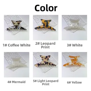 Detailed view of fish tail hair claw clips in six colors on glass surface