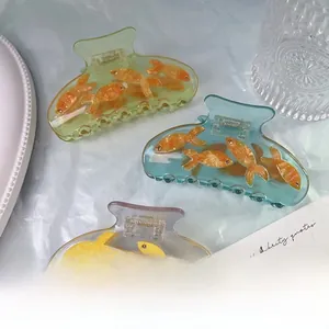 Detailed close-up of acetate shark hair clips featuring delicate 3D goldfish designs