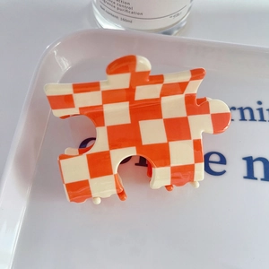Pince à cheveux en acétate en forme de puzzle avec motif à damier orange et blanc
