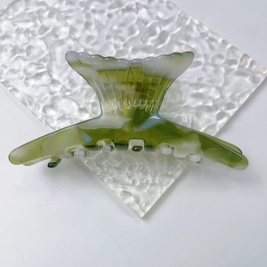 Detail of elegant fishtail hair claw clip in green marble acetate with secure metal spring