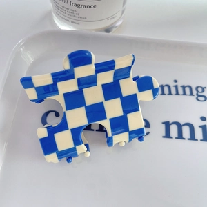 Gros plan d'une pince à cheveux en forme de puzzle avec motifs à damier bleu et blanc