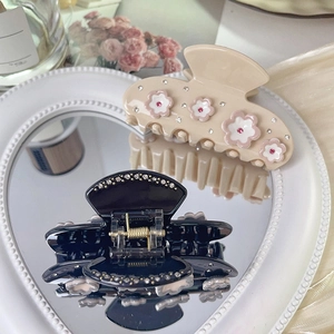 Elegant floral acetate hair claws with rhinestones on a mirror surface with dried flowers