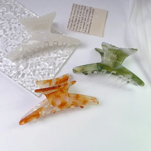 Detailed view of fishtail claw clips in white, green marble, and amber textures