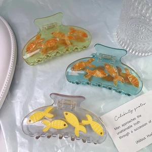 Detail of acetate shark hair clips featuring cute goldfish designs in pastel blue and green