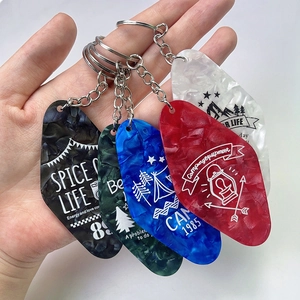 Close-up of hand holding acrylic diamond-shaped motel keychains in marble textures