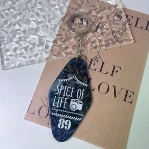 Macro detail of dark blue marble acrylic hotel key tag with white text and silver metal ring