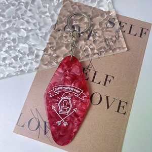Detail of red marble acrylic camping keychain with camp lantern and arrow illustrations