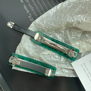Close-up of dark green resin hair clips with silver spring buckle and rhinestone detail