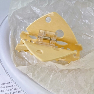 Dettaglio della molletta per capelli a forma di formaggio giallo su vassoio bianco