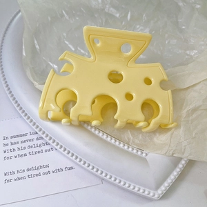 Vista dettagliata di un grazioso fermaglio giallo a forma di formaggio con fori realistici