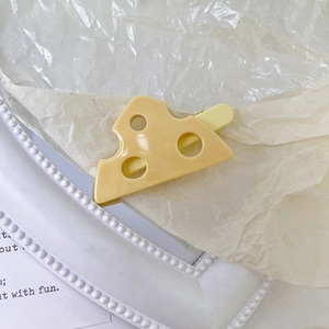 Dettaglio della molletta per capelli a forma di formaggio con texture gialla su sfondo